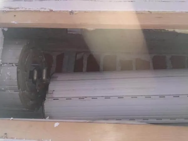 Beschädigte Decke mit freiliegenden Rohren und Leuchten.